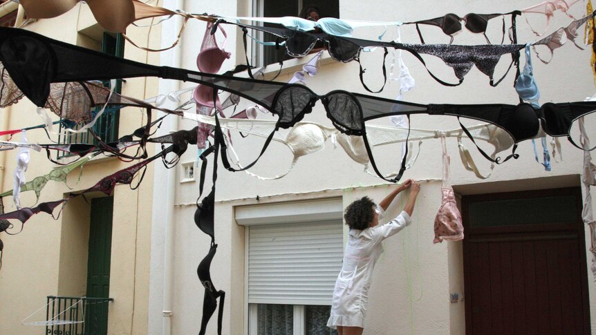A woman hangs bras along a street during a protest.