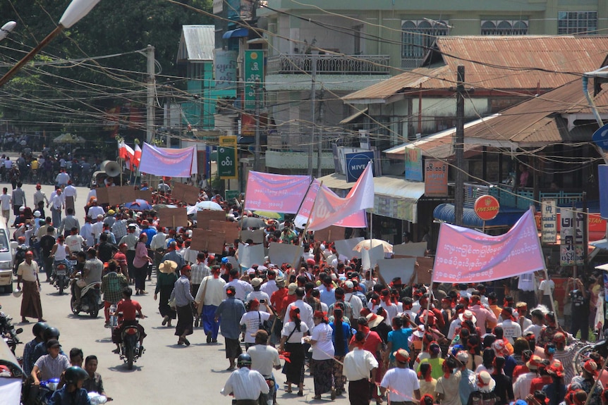 Hundreds of people marching with banners and flags.