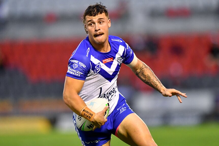 A Canterbury Bulldogs NRL player runs with the ball in his right hand.