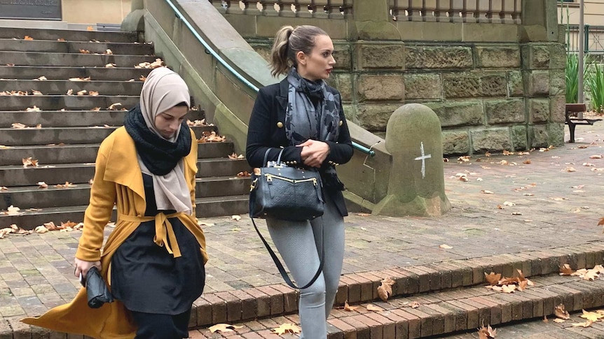Two women walking down stairs side by side.