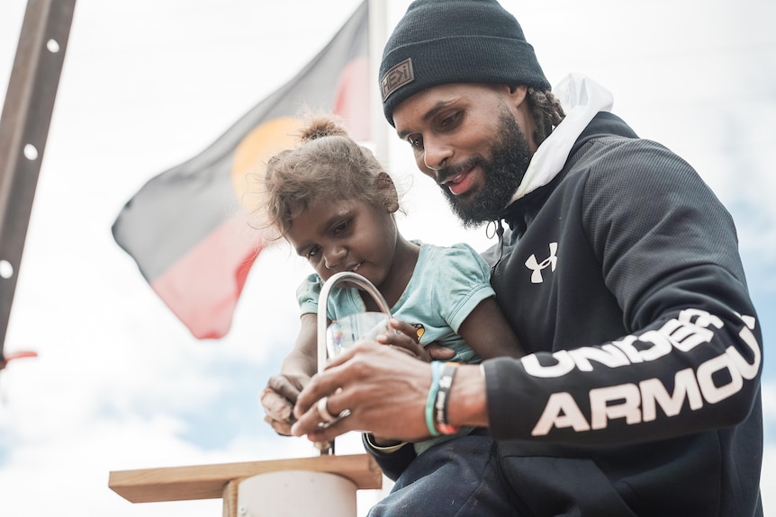 Patty helps a young child fill her glass with water.