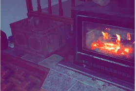 A fireplace on a tile floored room. The photo quality is low.