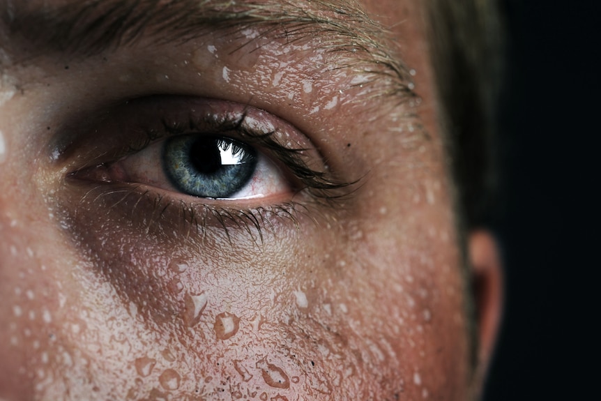 Close up of man's face and eye with sweat beads on skin