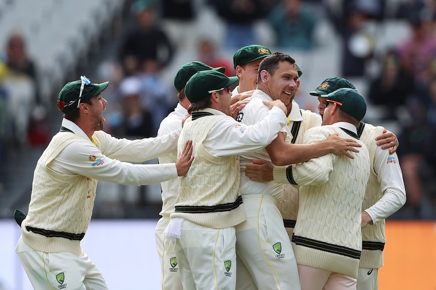 Scott Boland is hugged by several happy teammates