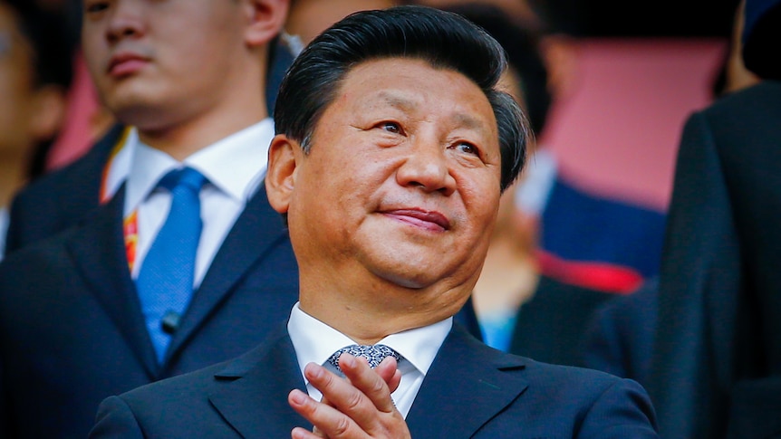 Xi Jinping in a suit, clasping his hands together 