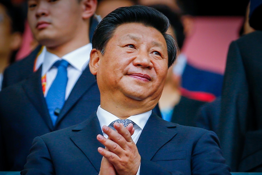 Xi Jinping in a suit, clasping his hands together 