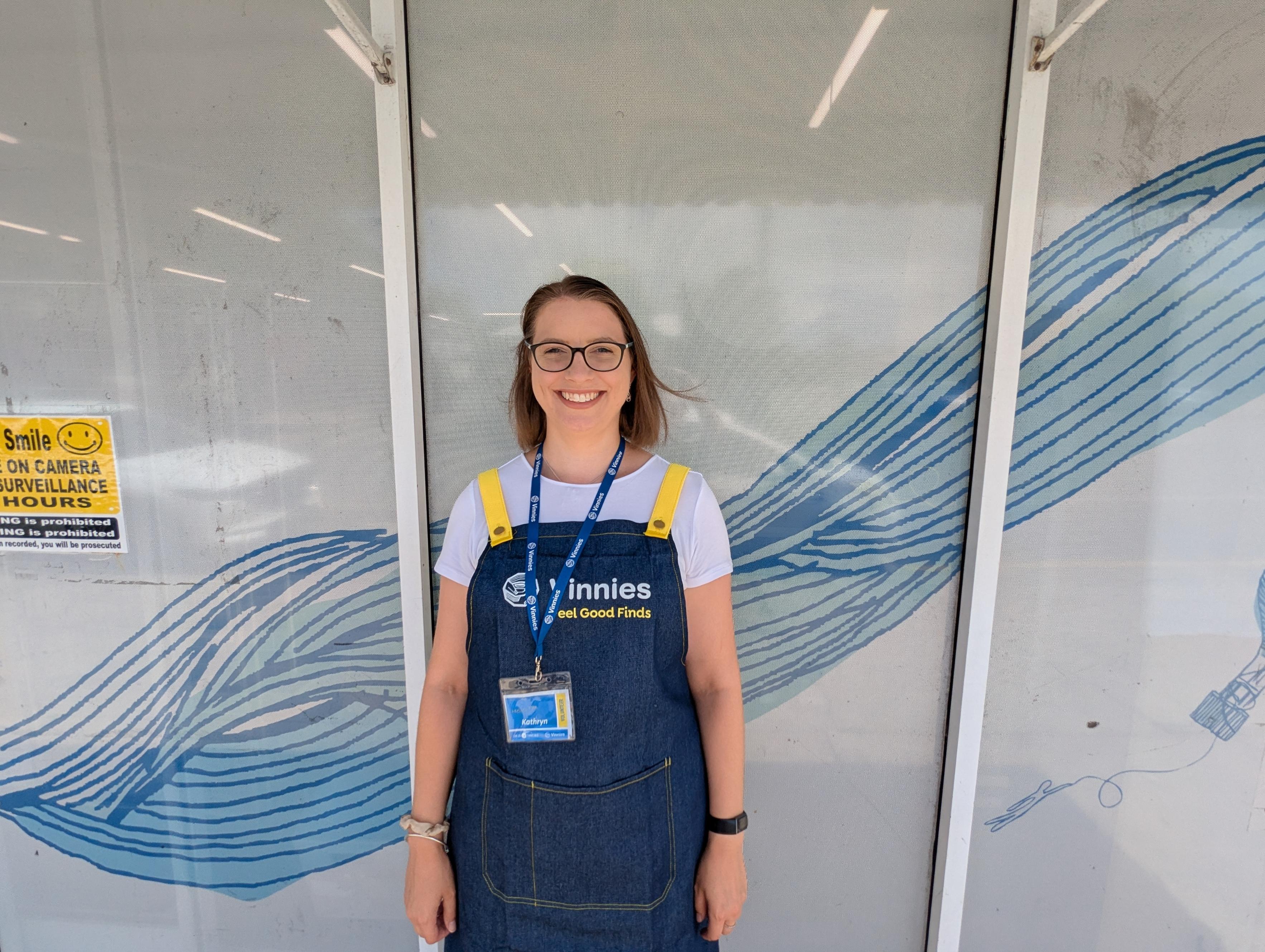 Una joven parada frente a la tienda con un cordón y un delantal