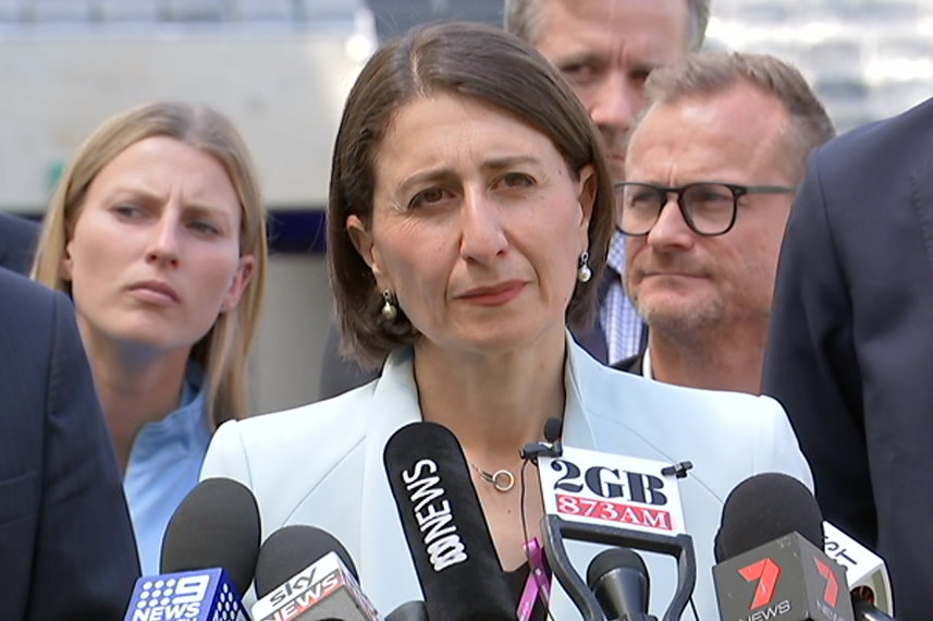 Gladys Berejiklian stands in front of media microphones.