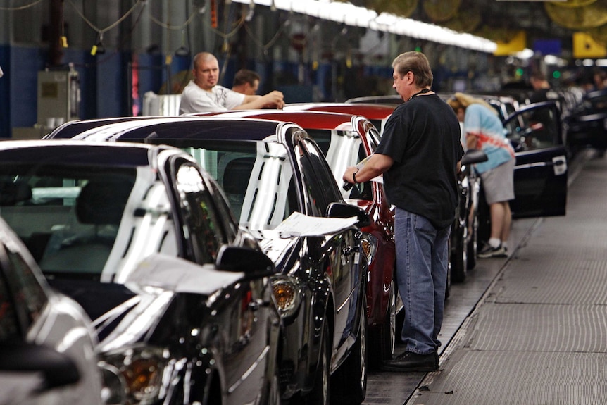Workers inspect cars on a production line