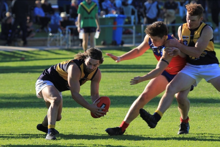 Three young footballer players fight for ball, left player is dodging two players on right