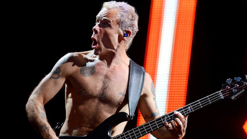 Flea of The Red Hot Chili Peppers playing a bass with no shirt on