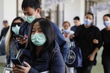 A group of people walking wear green masks on their mouths