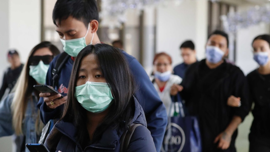 A group of people walking wear green masks on their mouths