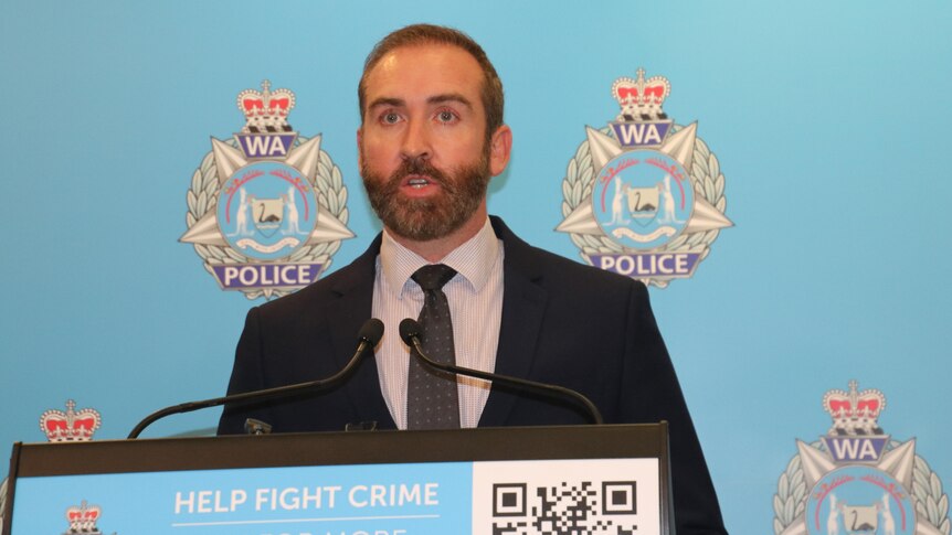 A detective wears a suit while he addresses media at a press conference