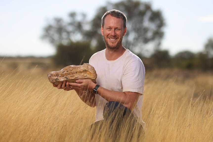 Man holds fossil skull in field