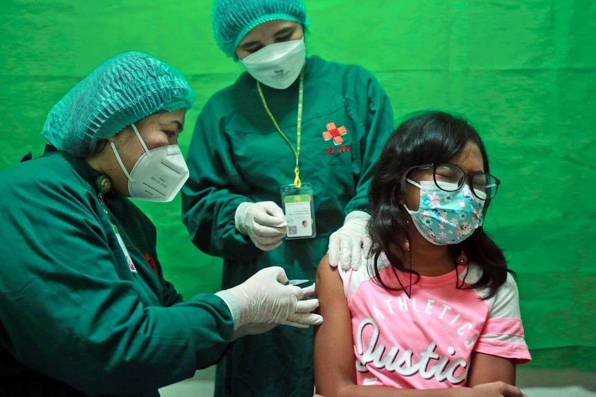 A young girl reacts to a shot of the Sinovac COVID-19 vaccine