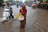 A motorist and a woman wade through a waterlogged street after heavy rains from Cyclone Tauktae in Ahmedabad, India.