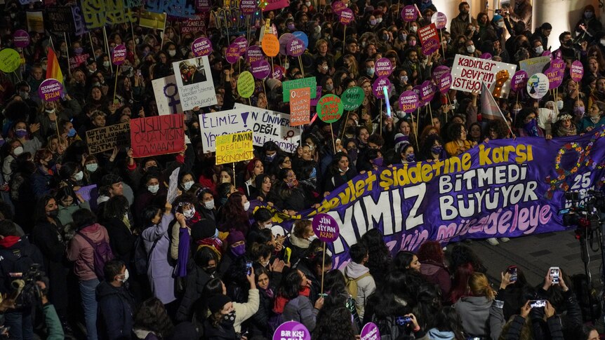 Thousands of women march and hold up signs in the street during a protest.