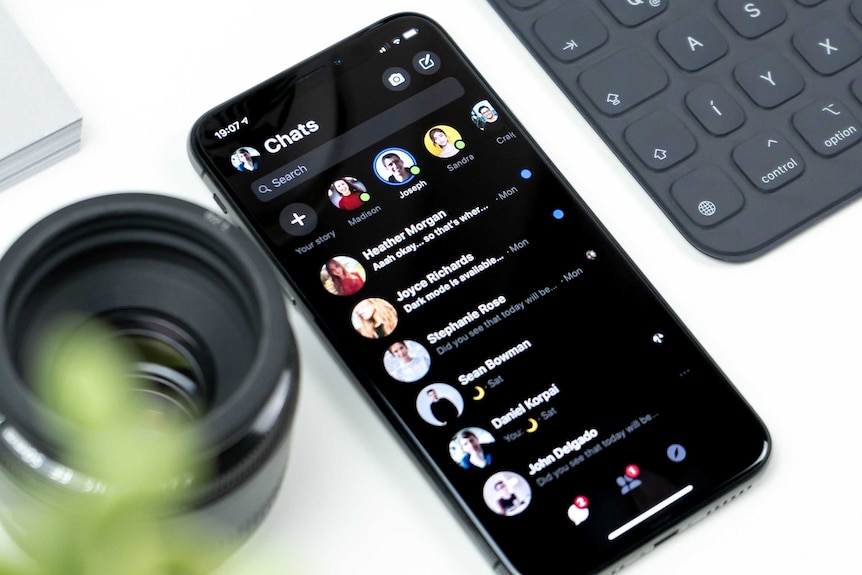 phone on a desk next to a tablet showing unread messages in the Facebook Messenger app