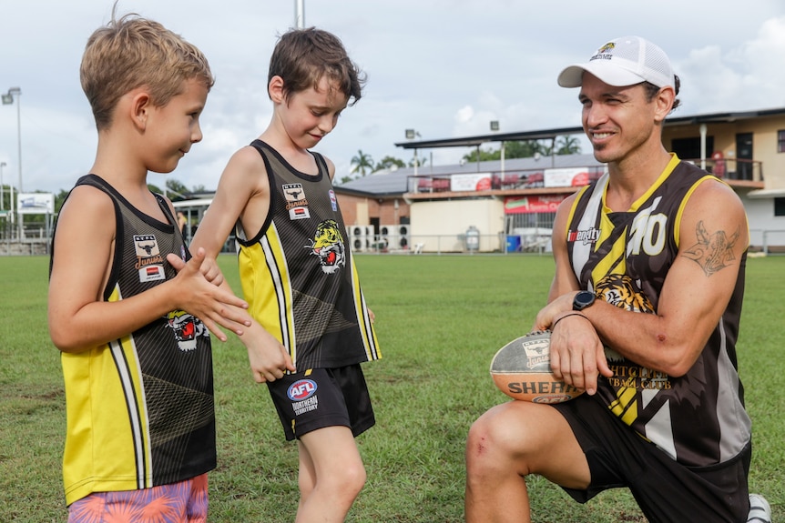 Cameron Ilett kneels down and chats his children Artiki Ilett and Will Cameron at the Nightcliff Football Oval.