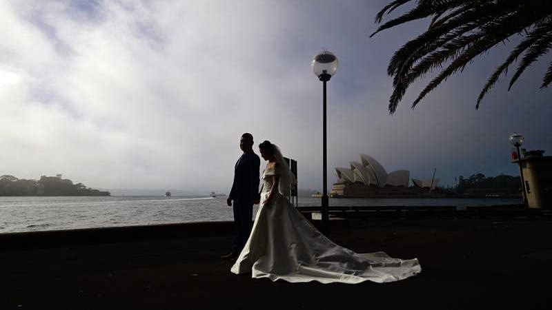 A couple in bridal dress with the opera house as backdrop.