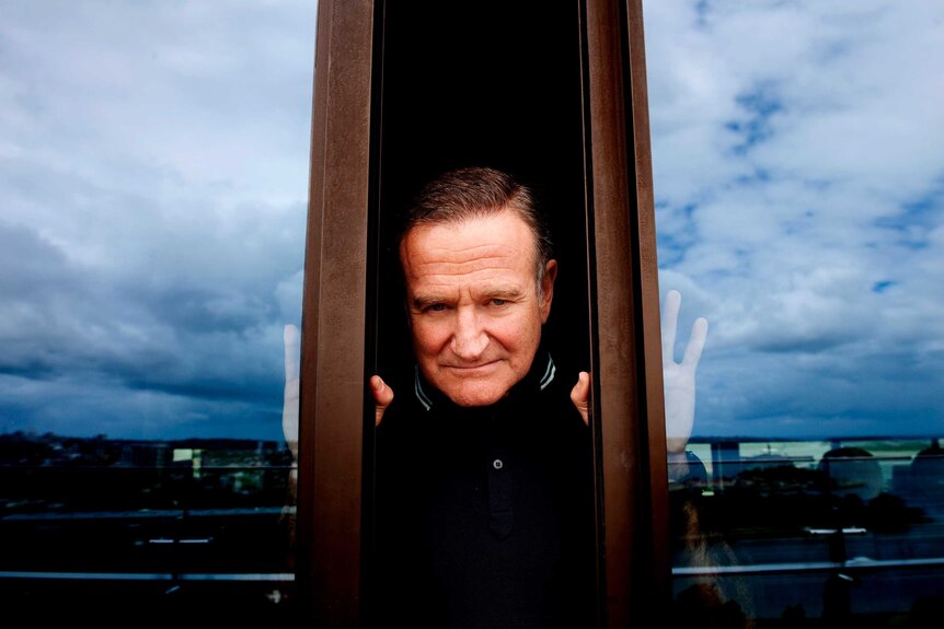 American actor and comedian Robin William poses for photographs in Sydney between two sliding doors reflecting the sky
