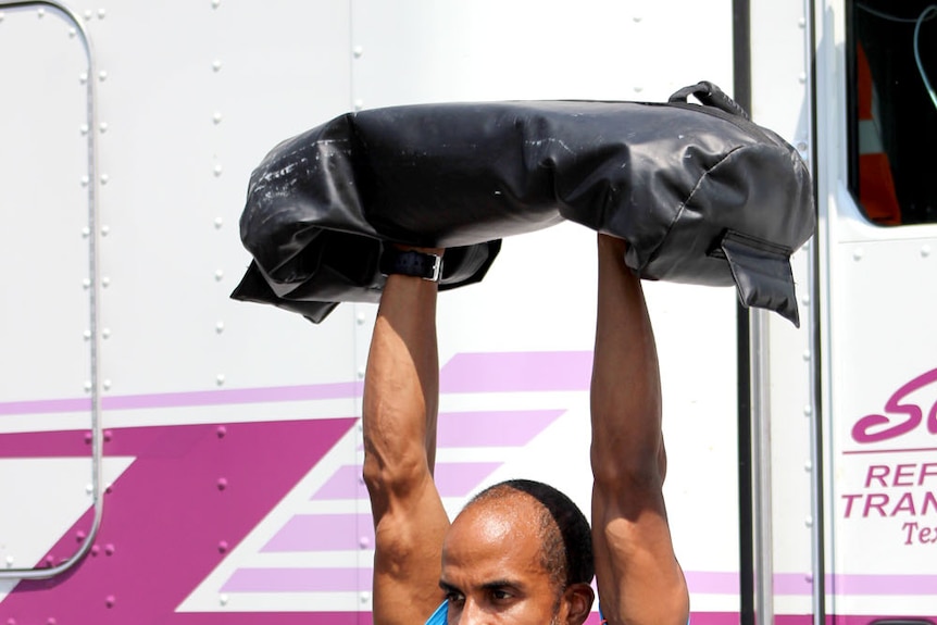 Siphiwe Baleka lifts a weighted bag above his head