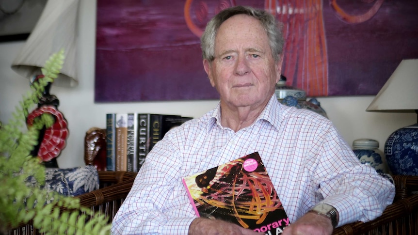 Man in white shirt hold a book and looks concerned.