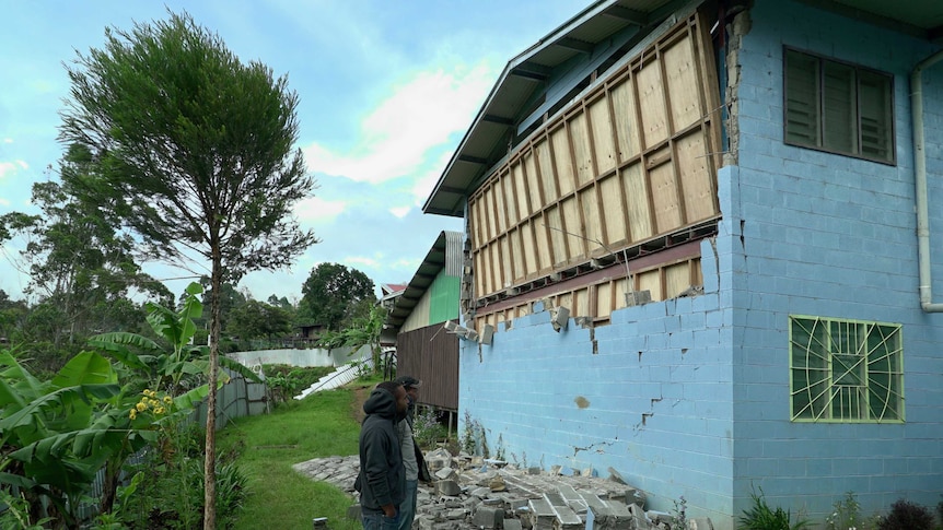 Students inspect damage to a wall at a nursing college