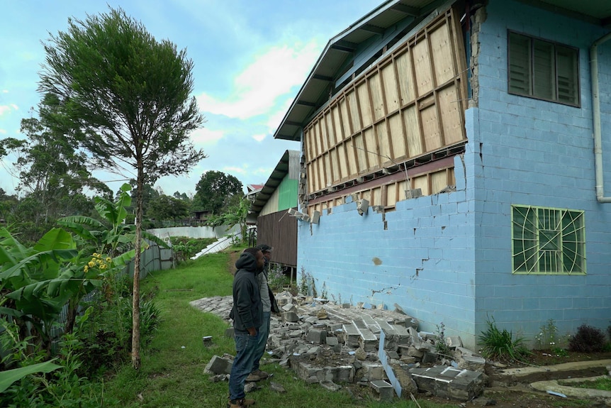 Students inspect damage to a wall at a nursing college