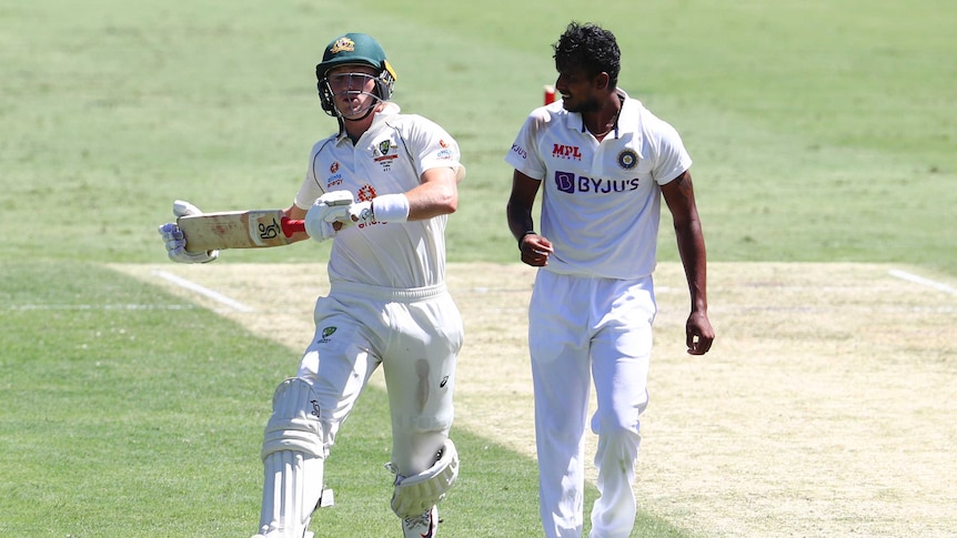 A  bowler looks at an opposing batsman as the batsman runs between the wickets