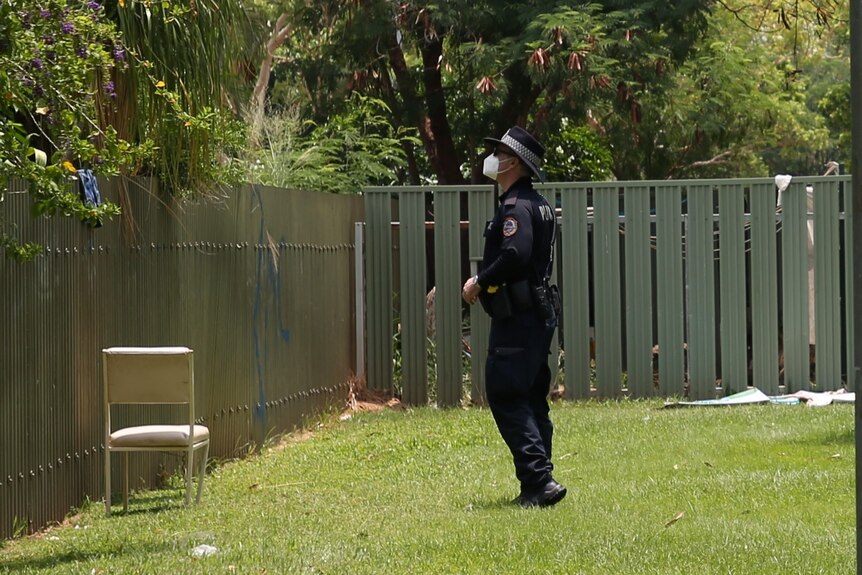 Police are walking through a lawn at a block of flats on Victoria Highway.