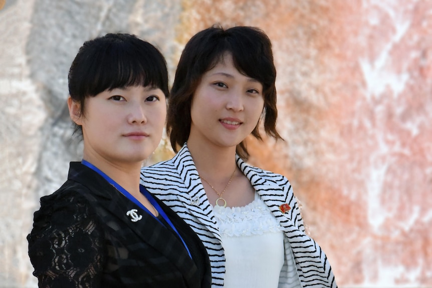 Two North Korean women pictured wearing Chanel and Kim badges