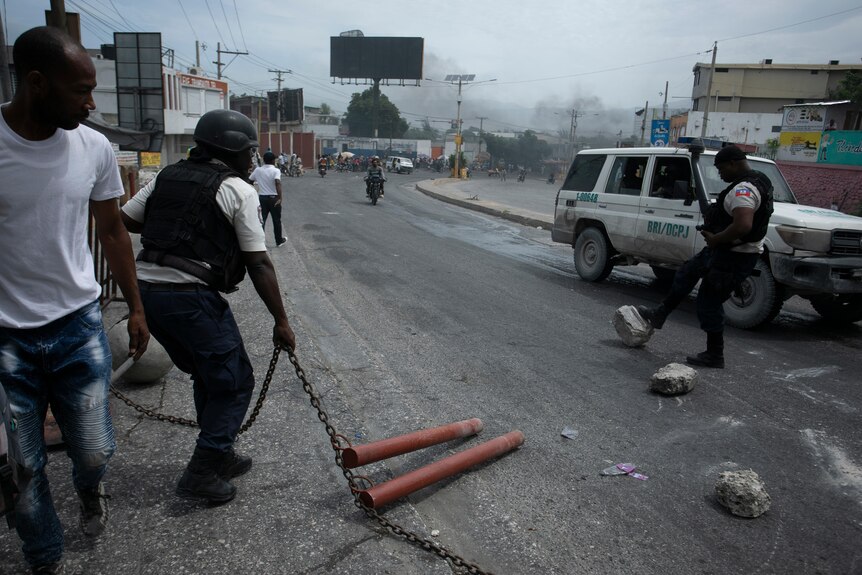 Police try to clear a roadblock of chains and stones set up by taxi drivers protesting fuel shortages, in Port-au-Prince.
