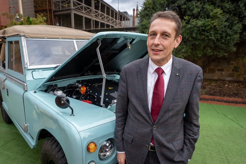 Man in suit infront of vintage blue car