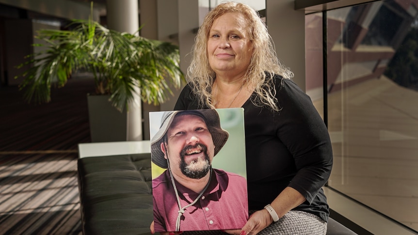 A woman holding a photo of a man.