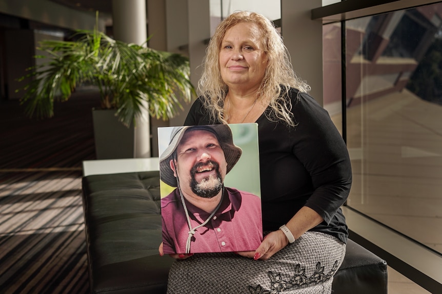 A woman holding a photo of a man.
