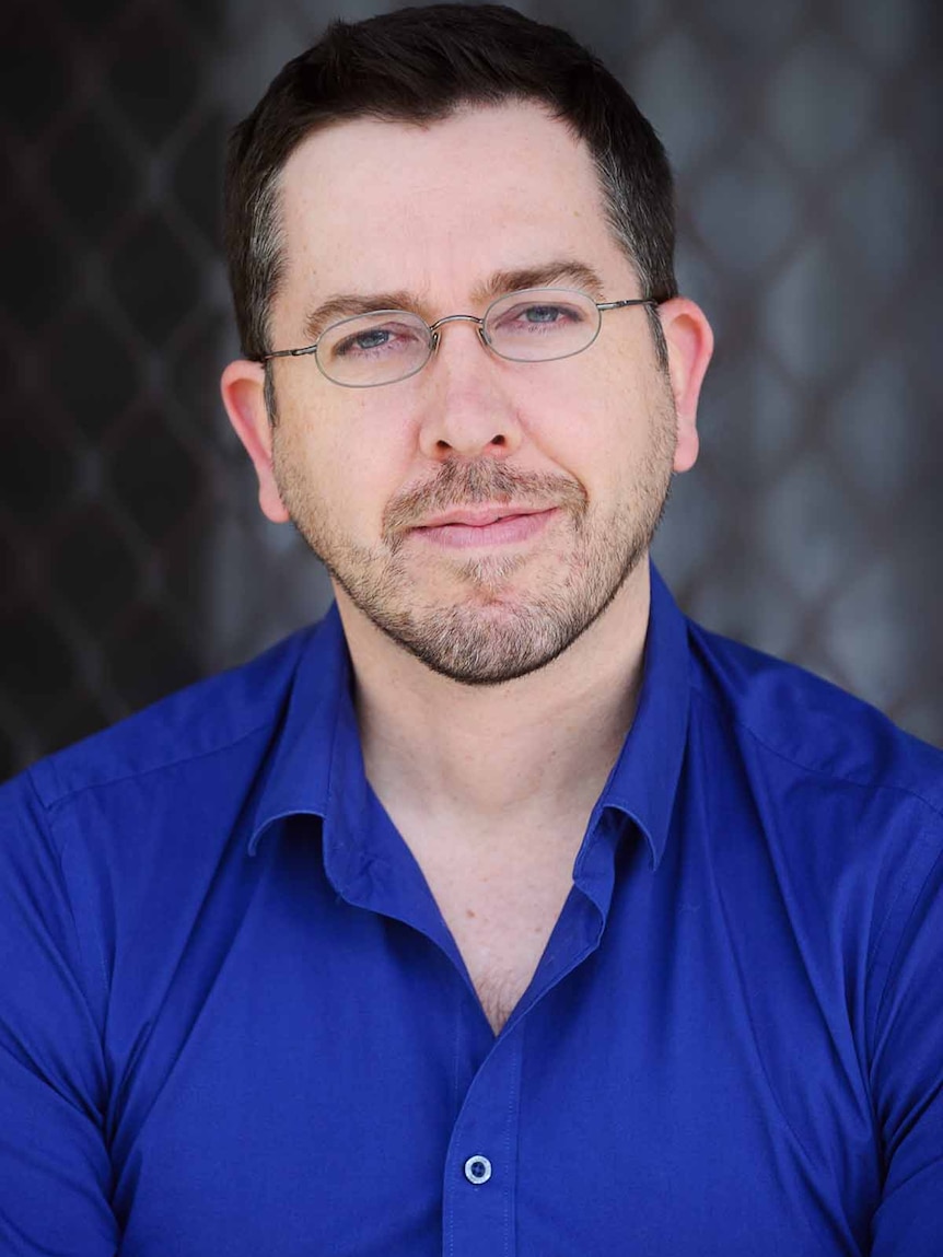 Portrait of a middle-aged man with dark hair and glasses.