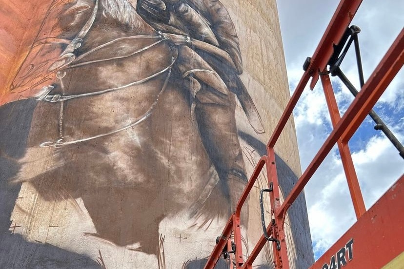 A man riding a horse painted on a silo. 