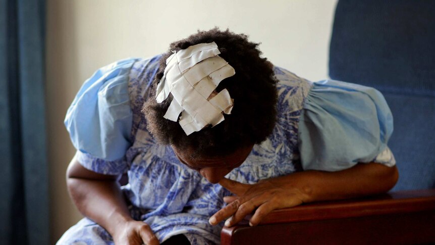 A victim of domestic violence shows her head wound patched up with tape in a women's shelter in Port Moresby.