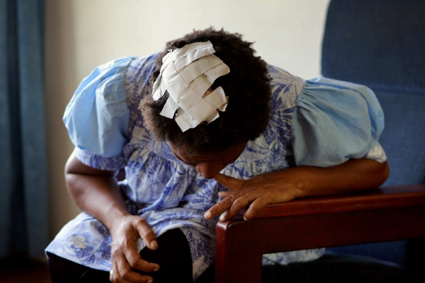 A victim of domestic violence shows her head wound patched up with tape in a women's shelter in Port Moresby.