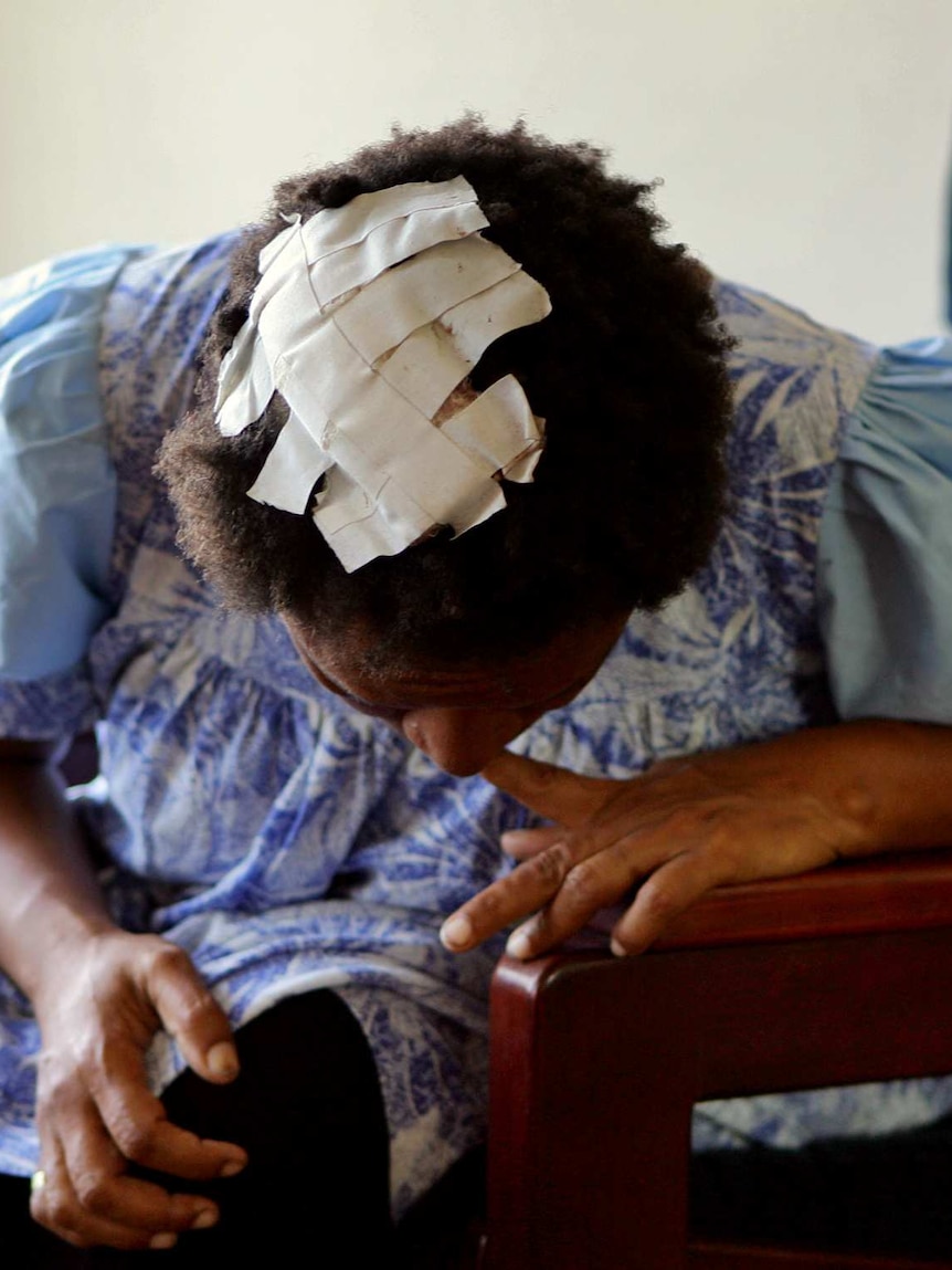 A victim of domestic violence shows her head wound patched up with tape in a women's shelter in Port Moresby.