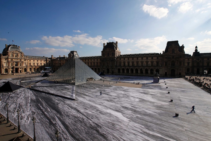 The art creation of French street artist JR is pictured in the courtyard of the Louvre Museum near the glass pyramid