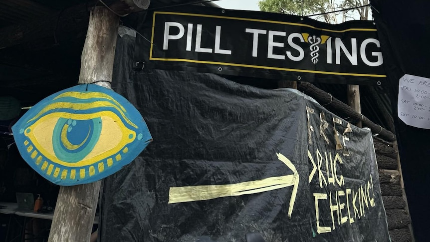 a tent with black shadecloth around it saying 'pill testing'