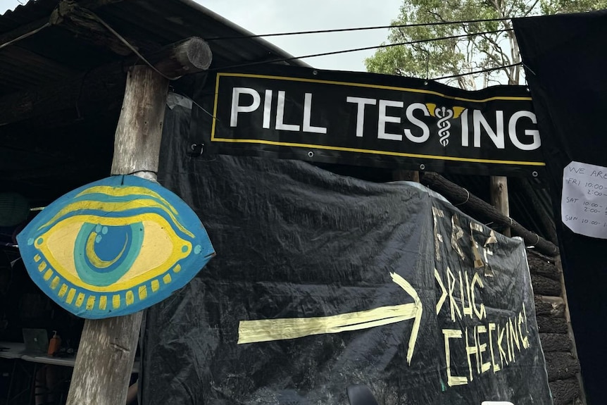 a tent with black shadecloth around it saying 'pill testing'