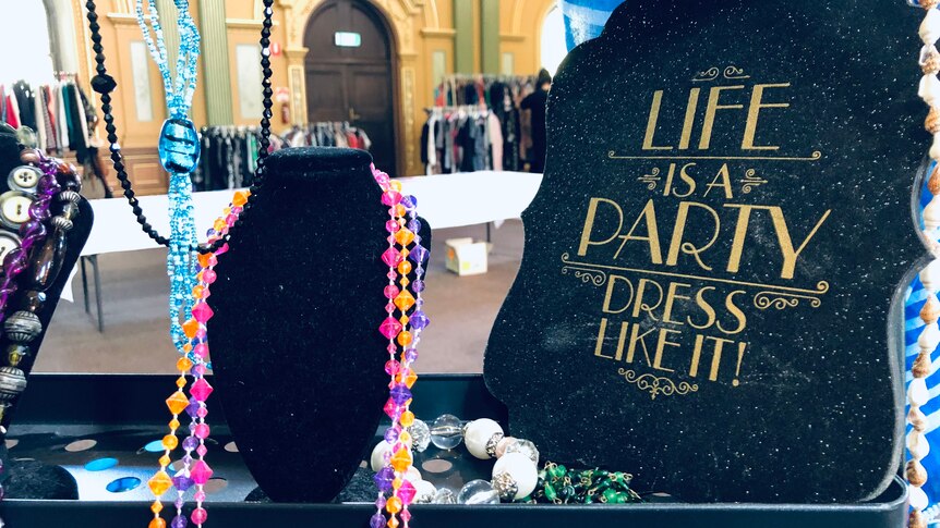 a sign that reads "life is party, dress like it" next to some beads