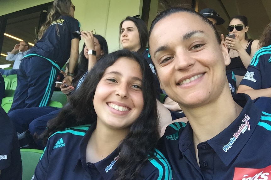 Two soccer players take a selfie at a football match