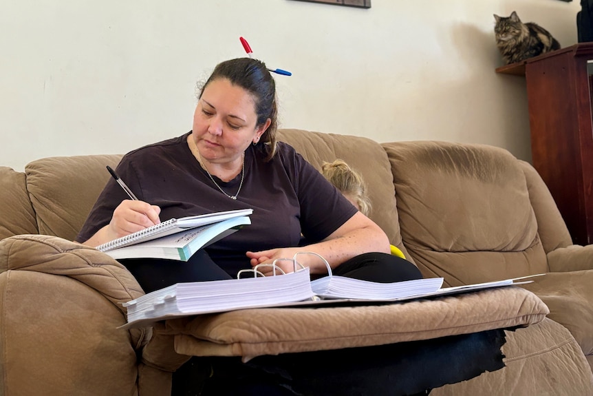 A woman sits on the couch and studies. 