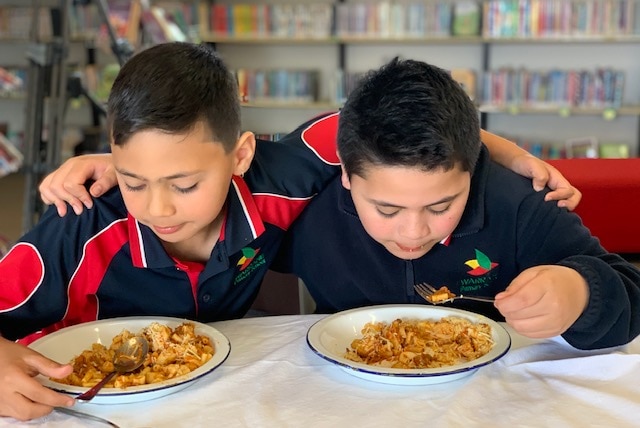 Two kids eating lunch at school.