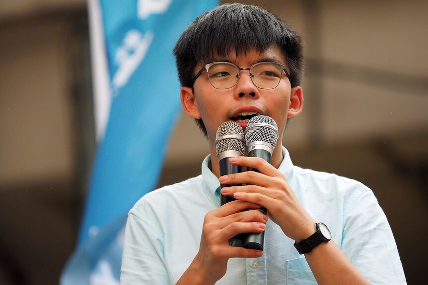 Joshua Wong speaks into two microphones.